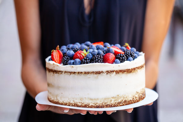 Frau im blauen Kleid hält einen Beerenkuchen