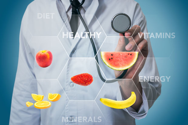 Wissenschaftler mit Stethoskop und verschiedenen Früchten