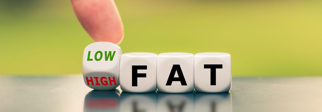 Low Fat Drei Würfel, die das Wort "FAT" anzeigen, der vierte (erste) Würfen wird mit dem Finger gekippt und es erscheint entweder "LOW" oder "HIGH"-FAT, Low Fat
