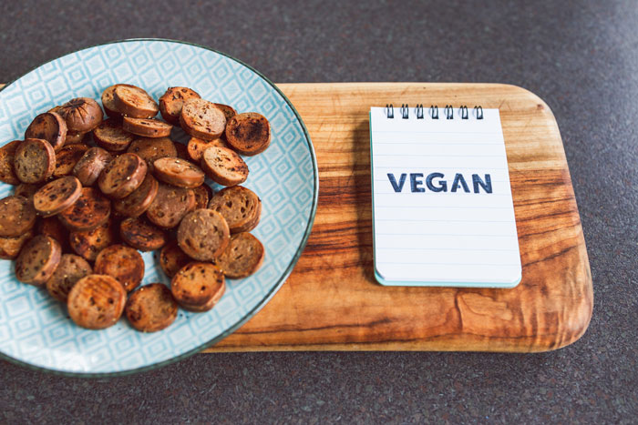 Vegane gebratene Wurst in Scheiben geschnitten, daneben ein Memo mit der Aufschrift "VEGAN"