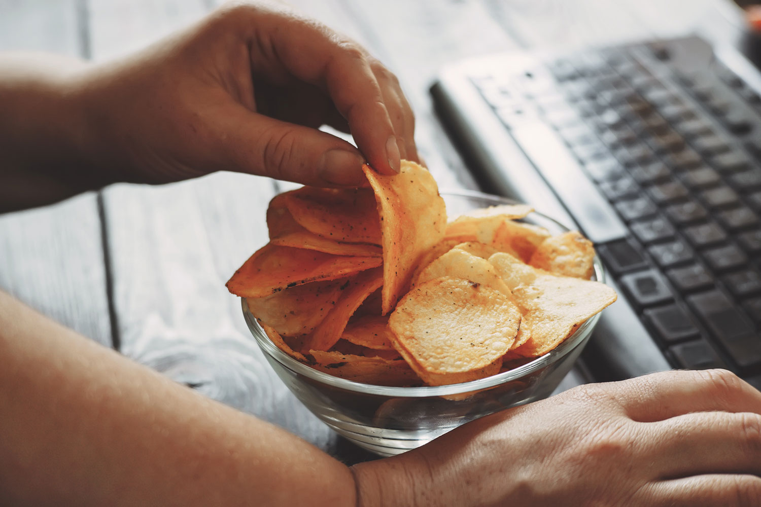 Hand nimmt Chips aus einer Schale