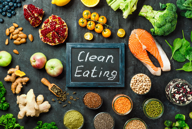 In der Mitte von Lebensmitteln liegt eine Tafel auf der Clean Eating drauf steht
