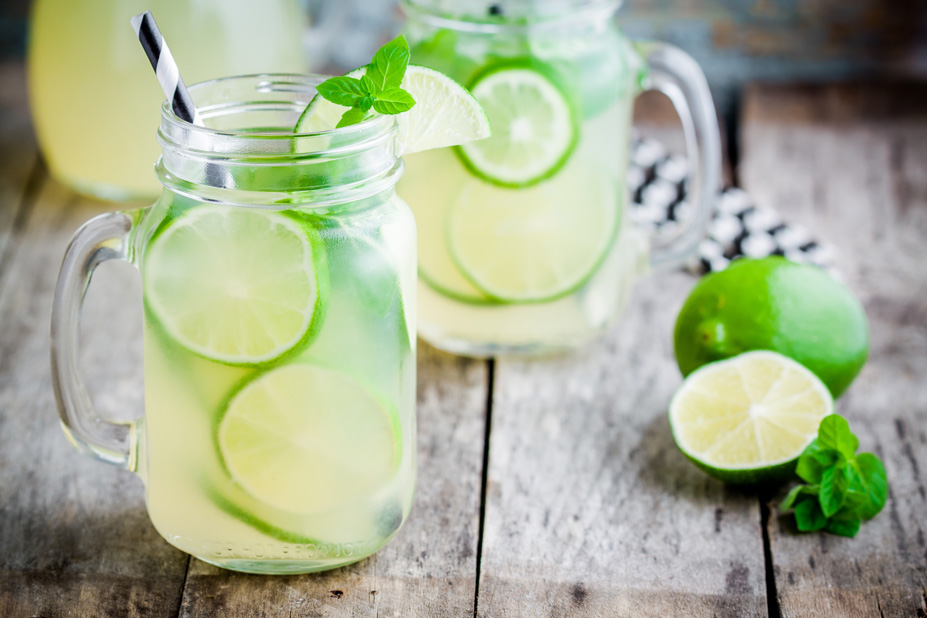Infused Water Zwei Gläser mit Wasser, die mit Limettenscheiben gefüllt sind.