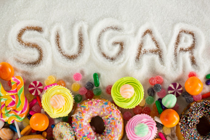 In Zucker ist das Wort Sugar geschrieben. Darunter liegen Süßigkeiten.
