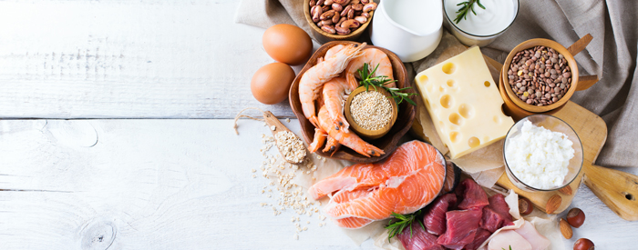 biologische wertigkeit Verschiedene eiweißreiche Lebensmittel liegen auf einem Tisch. Z.B. Eier, Linsen, Quark, Fisch, Fleisch, Haferflocken.