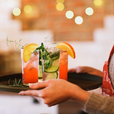 Tablett mit Cocktails von einer Kellnerin getragen