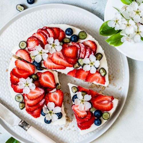 Fruchtiger Erdbeerkuchen reich verziert mit Blaubeeren und Kirschblüten